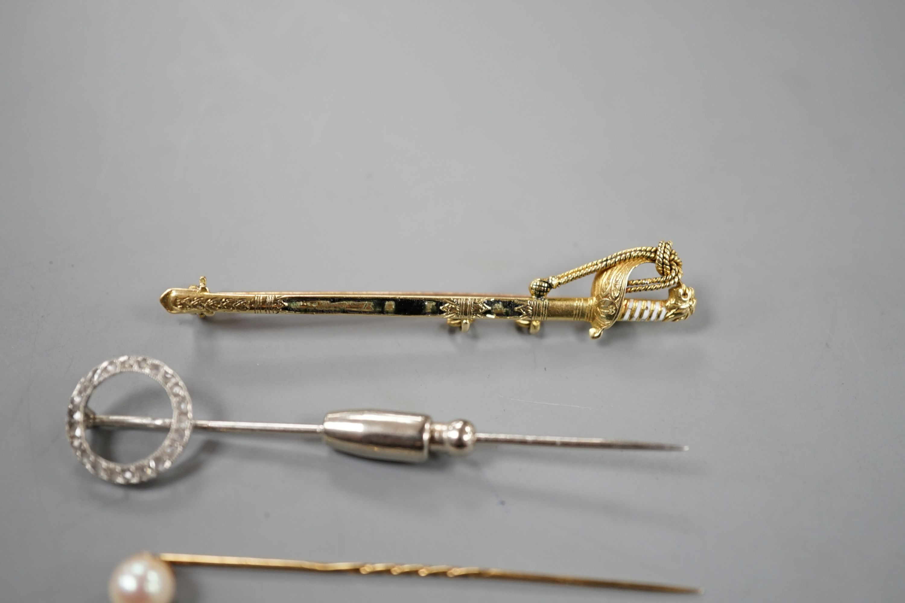 A French white metal (poincon mark for platinum) and diamond set tie pin, 64mm, gross 3.4 grams, a 15ct and enamel(a.f.) sword brooch, gross 4.7 grams and toe 9ct pins, one with cultured pearl, gross 3 grams.